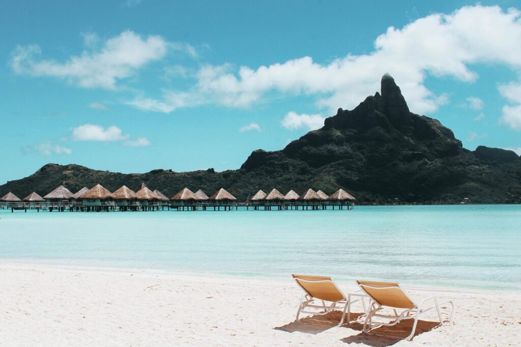Strand met ligstoelen aan turquoise water in Frans-Polynesië