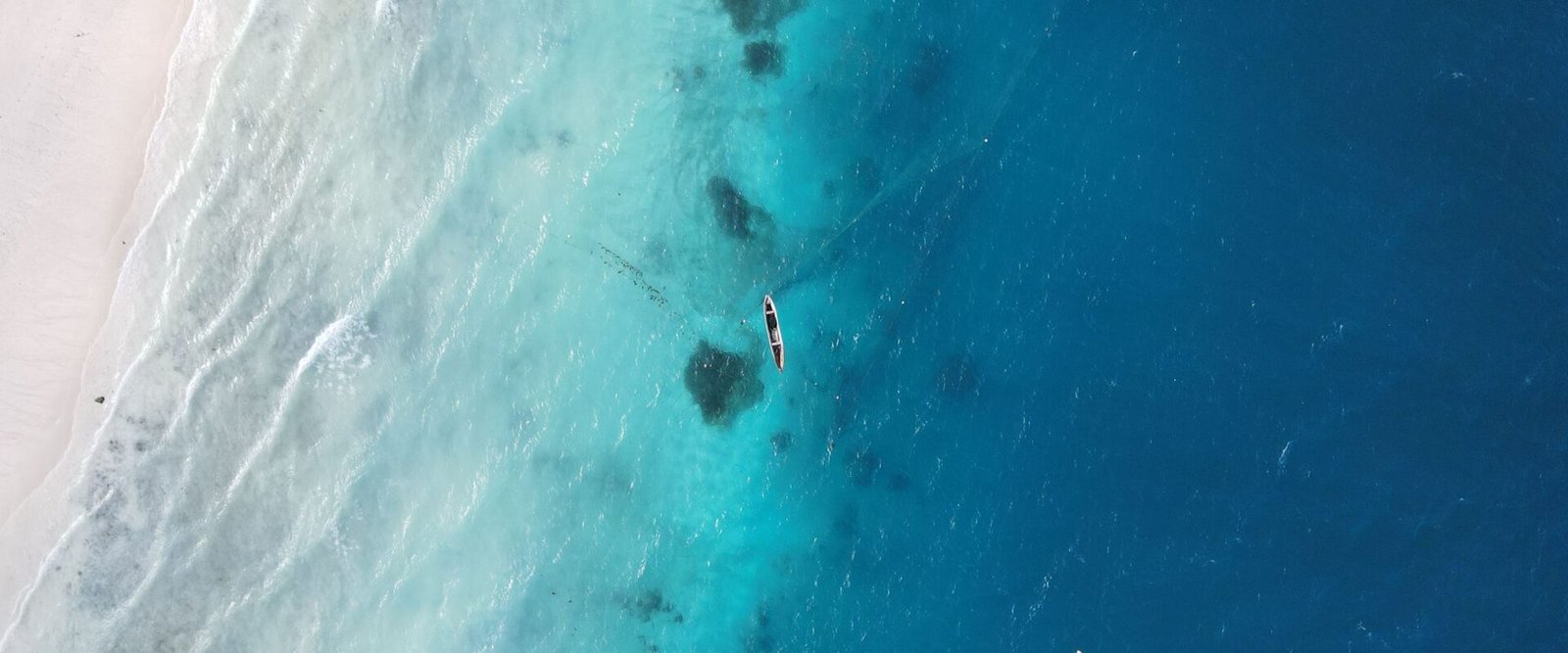 Het rif en turquoise water voor de kust van Zanzibar vanuit de lucht