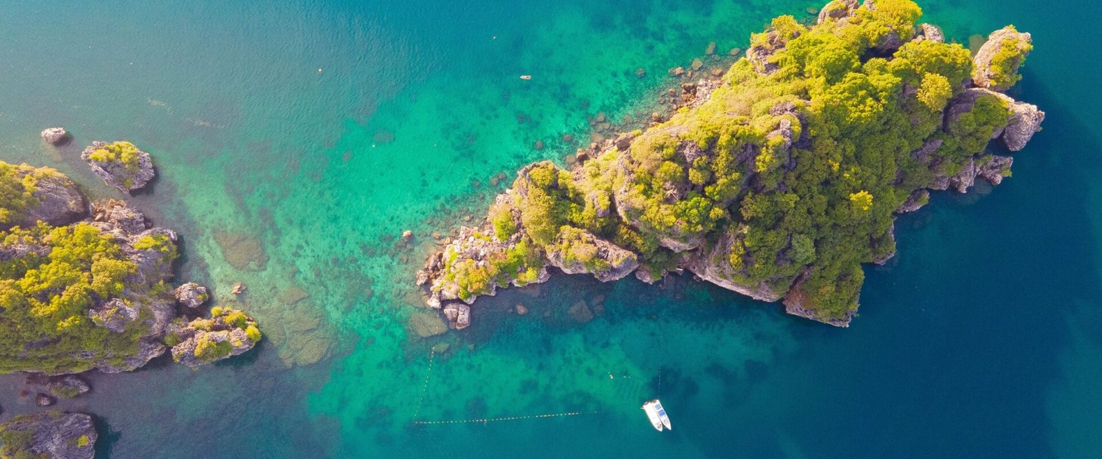 Rotsig eiland in turquoise water van bovenaf