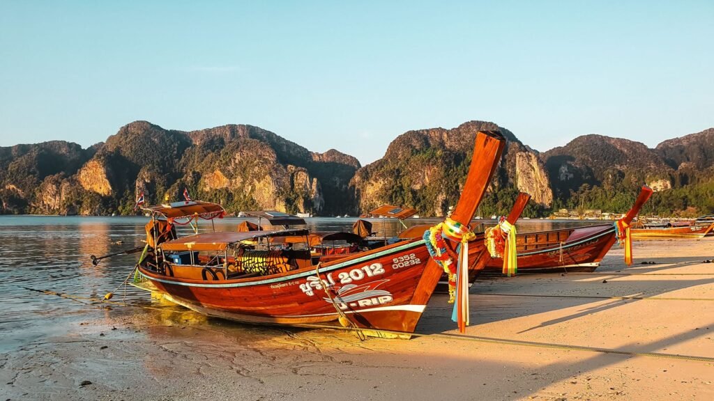 Longtailboten op een Thais strand bij zonsondergang