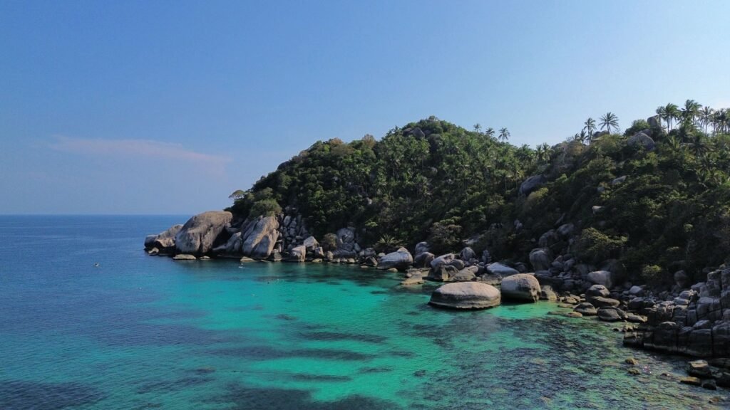 Granietrotsen en helder water aan de kust van Koh Tao