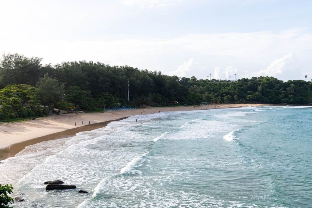 Strand met golven en groene heuvels op Phuket