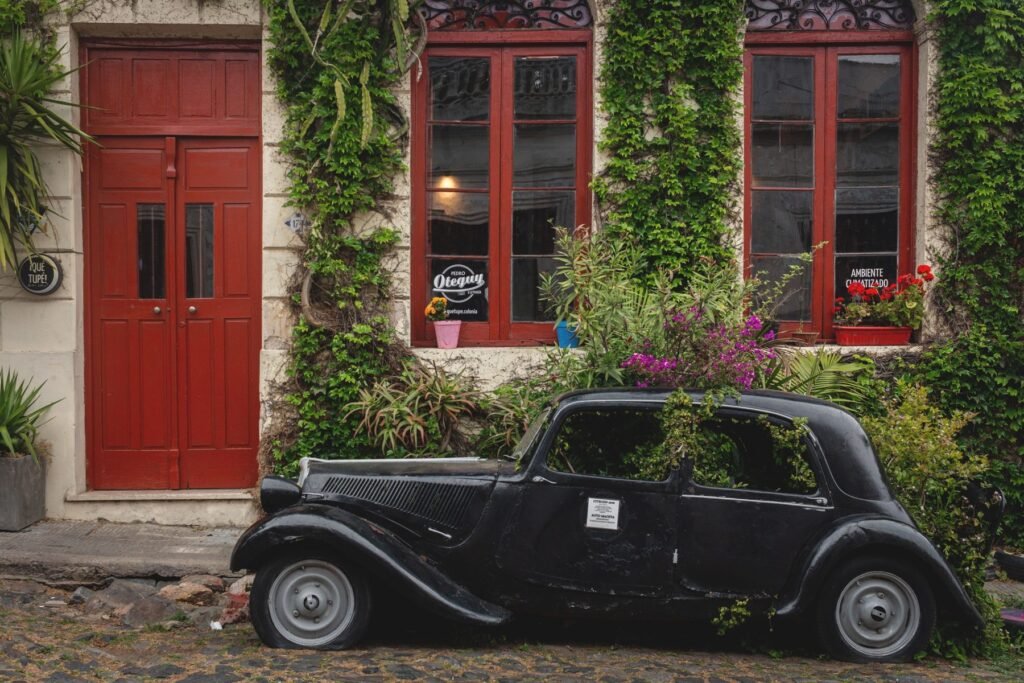 Klassieke zwarte auto voor een gevel met klimop in Colonia del Sacramento